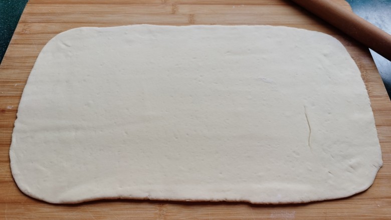 红糖花卷,发酵好的面团放到面板上，手揉排气，揉至面团光滑，用擀面杖擀成一个长方形的面片。