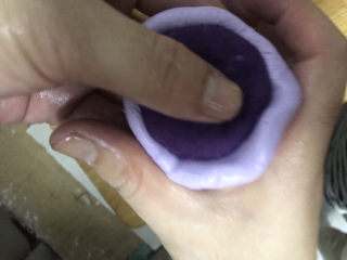 紫薯芝麻饼,一手大拇指按住紫薯馅，转动面坯，另一个手用虎口慢慢收紧