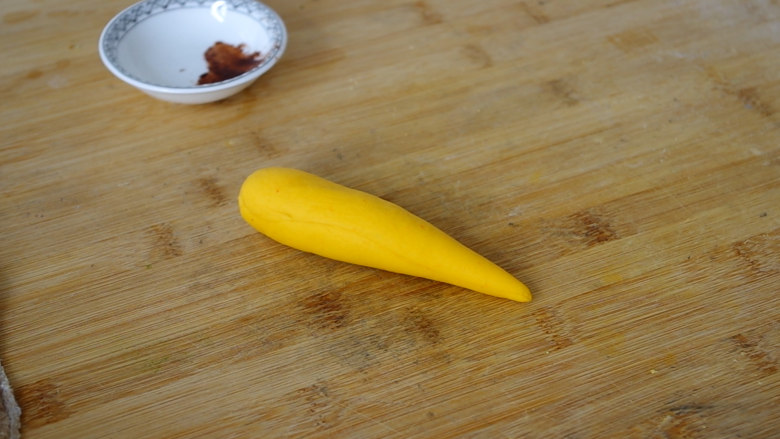 胡萝卜馒头,先取其中一个黄色面团揉均匀后搓成胡萝卜的形状，可以搓的长一些，因为在蒸的时候胡萝卜会发酵。