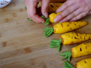 胡萝卜馒头,把绿色的叶子放在黄色面团的顶部，黄色面团顶部可以用筷子戳个小洞，方便固定叶子。