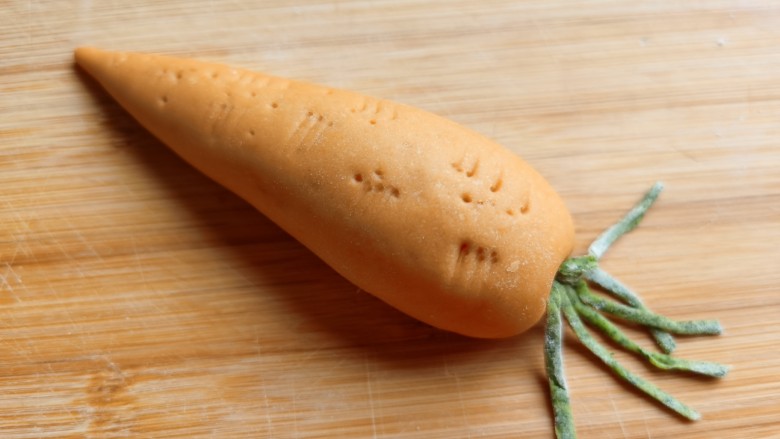 胡萝卜馒头,取两三根细条对折，塞到胡萝卜粗的一头上，一个带着绿色萝卜缨的胡萝卜完成了。