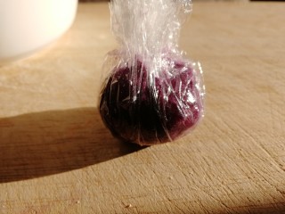 紫薯芝麻饼,挖一汤匙紫薯，放在保鲜膜上，包紧成球。