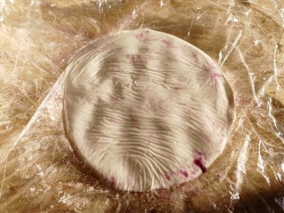 紫薯芝麻饼,取一个糯米面团，放在两个保鲜膜中间，压按成饼。