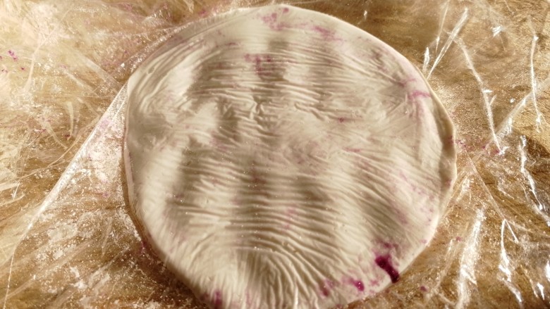 紫薯芝麻饼,取一个糯米面团，放在两个保鲜膜中间，压按成饼。