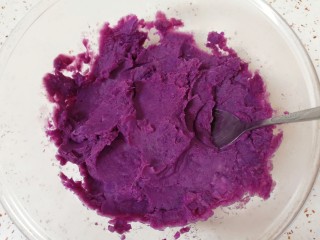 紫薯芝麻饼,蒸熟的紫薯放入大一点的容器里，用勺子压成紫薯泥。