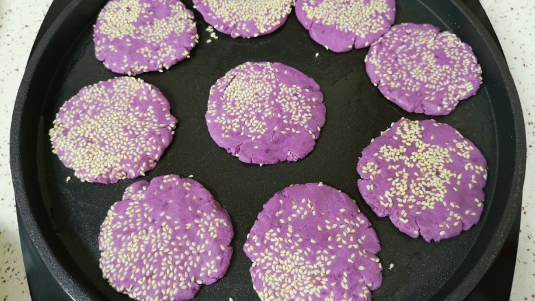 紫薯芝麻饼,电饼铛预热，刷上一层食用油，放入做好的紫薯芝麻饼。