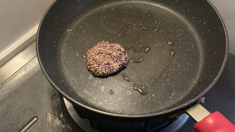 紫薯芝麻饼,把搅拌均匀的紫薯泥压成圆形薄饼，两面粘上芝麻，放入锅中，小火煎烤