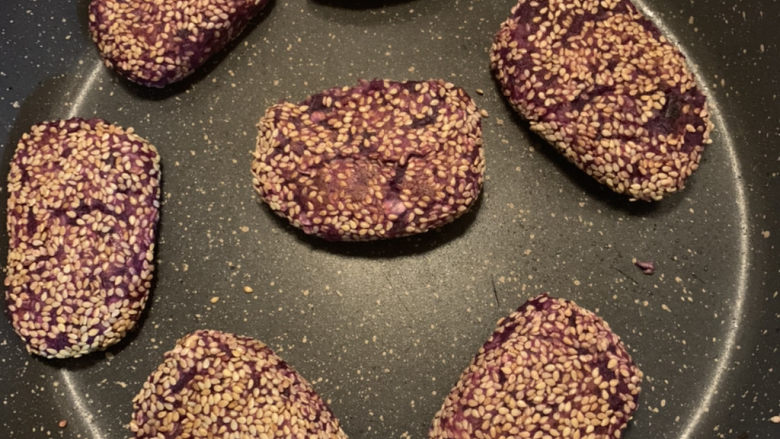 紫薯芝麻饼,翻面继续煎烤至芝麻变色，紫薯饼成型