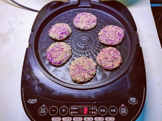 紫薯芝麻饼,煎烤机先预热刷油，将饼胚放入 煎至一面定型后翻另一面。