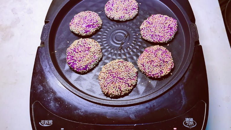 紫薯芝麻饼,煎烤机先预热刷油，将饼胚放入 煎至一面定型后翻另一面。