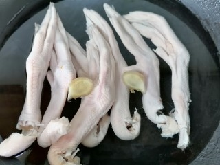 卤鸭爪,将鸭爪放入锅内焯水，放两片生姜去腥