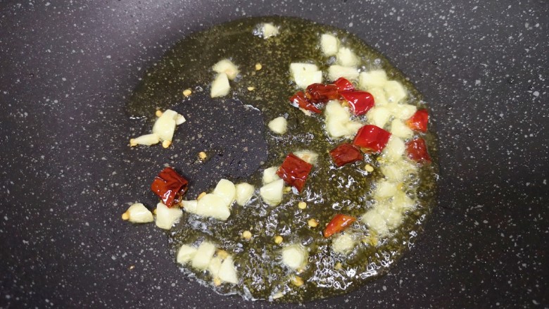 毛豆烧茄子,炒锅内倒适量的食用油烧热，下入大蒜和干红辣椒炒香。