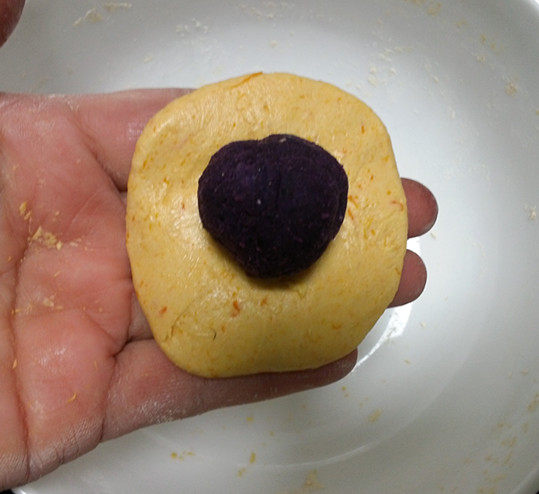 南瓜紫薯包,取一份南瓜皮压扁，放上紫薯球