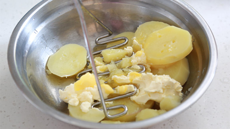 蓝莓土豆泥（芝士双薯泥）,蒸好后趁热先取出土豆放大盆中分别加进一半芝士和黄油压成泥；