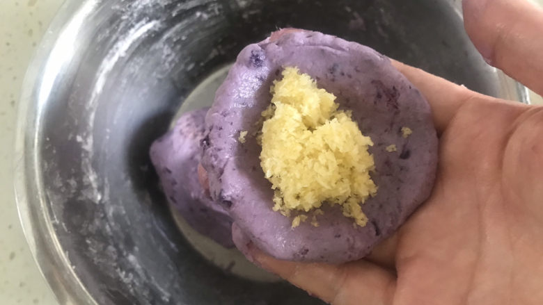 紫薯椰蓉球,揪一块面团用手压成圆形饼状，包入馅料