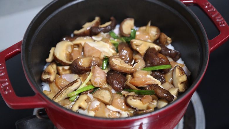 香菇滑鸡煲仔饭,将香菇和肌肉均匀的铺上米饭上，继续焖煮约10分钟