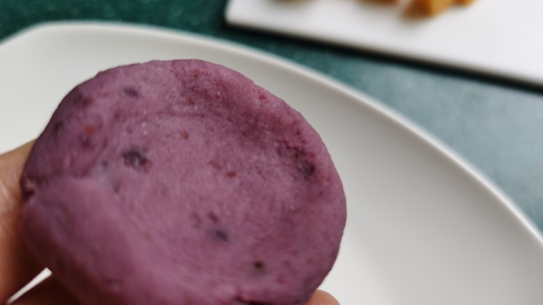 紫薯椰蓉球,取一勺紫薯泥，搓成圆形后，将中间按压出一个坑。