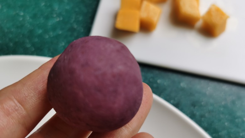 紫薯椰蓉球,将芒果丁包入紫薯里，用手搓成圆球。