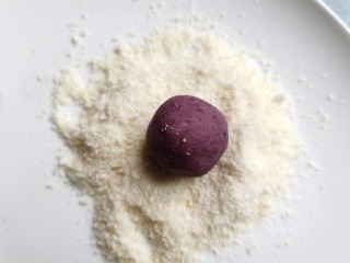 紫薯椰蓉球,将椰蓉倒入盘中，放入一个紫薯球，表面均匀的裹上一层椰蓉。