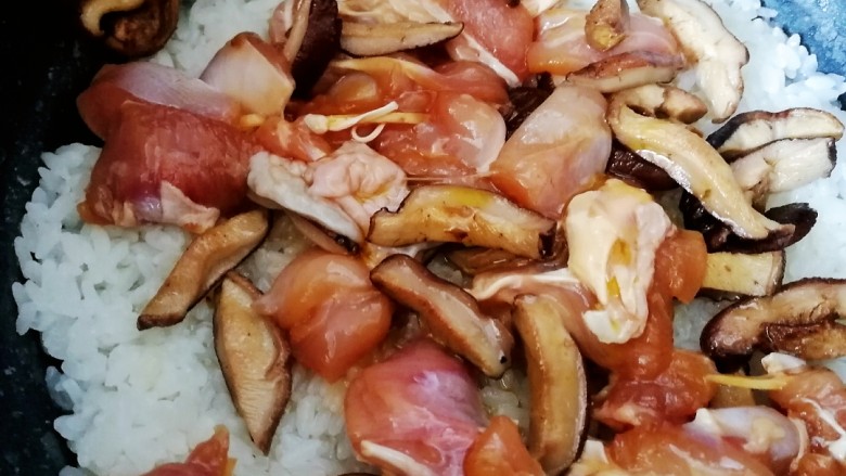 香菇滑鸡煲仔饭,饭煮到六七分熟，放入香菇和鸡肉，把料汁也浇在饭上，继续煮至跳闸。