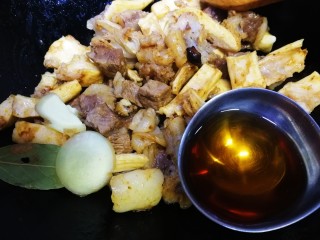 胡萝卜炖牛腩,放入香叶、姜片、牛腩和板筋文火炒香，放入一大勺料酒烹香。