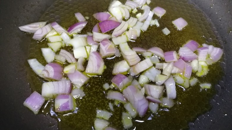 番茄口蘑火腿意面,平底锅倒入适量油，放入圆葱碎，文火炒透明。