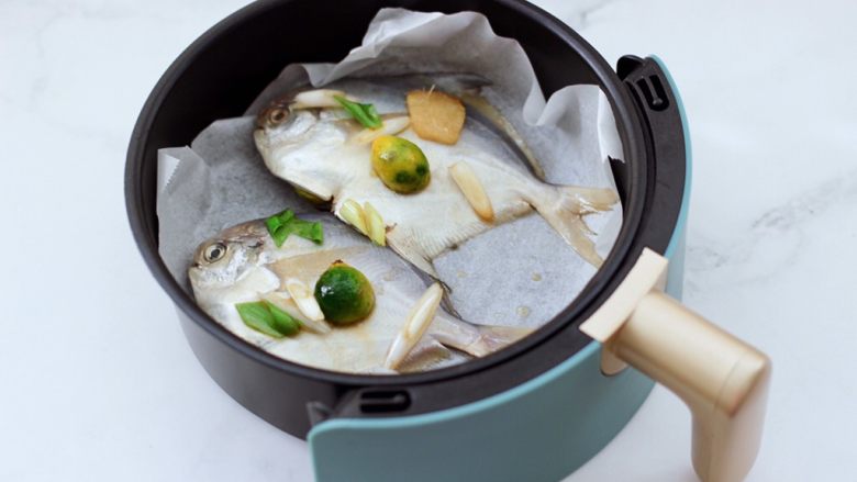 家常孜然烤银鲳,柏翠空气炸锅165度提前预热10分钟后，铺上油纸，把腌制好的银鲳鱼放入炸篮里。