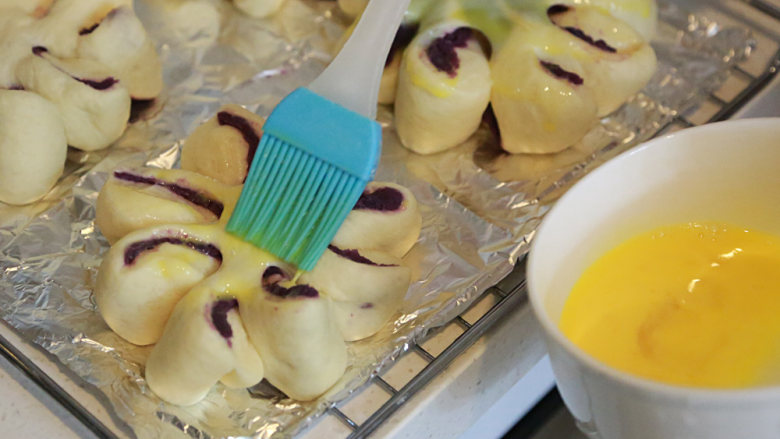 南瓜紫薯包,刷上蛋液，32L烤箱上150度下180度，置下二层，烤20分钟，最后几分钟改180度上色。
