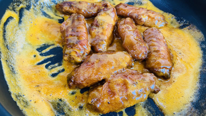 蛋黄焗鸡翅,放入煎熟的鸡翅均匀裹上金沙咸蛋黄调料