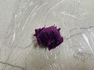 紫薯椰蓉球,取一保鲜膜摊平，放上一勺紫薯泥，把保鲜膜拧紧，成了一个小球状。再用手调整一下形状