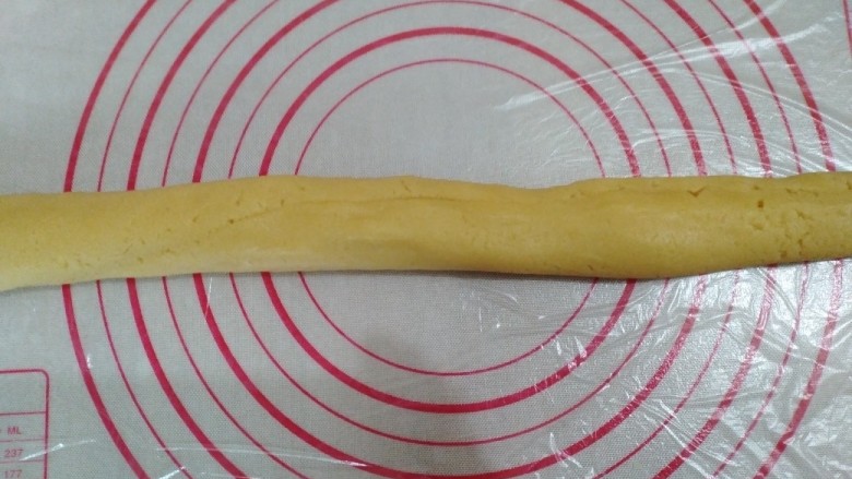 香芋酥,揉面垫上铺一张保鲜纸，面团放到揉面垫上，搓成和香芋泥同样长度的长条