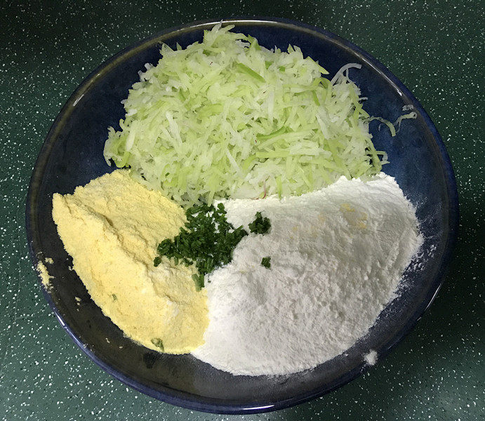 黄金玉米饼,碗中放入萝卜丝、玉米面和普通面粉，再加入盐和葱花