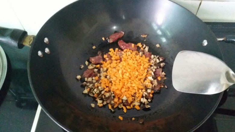 电饭煲腊肠饭,将胡萝卜和香菇放进锅里小炒片刻，放点盐