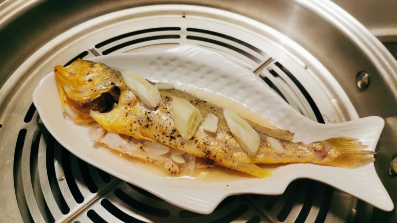 清蒸黄鱼,取出倒掉汤水和葱片。