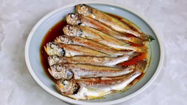 香辣小黄鱼,取出蒸好的鱼，把姜丝葱段夹掉，盘子里的汤汁倒掉，淋上一勺生抽。