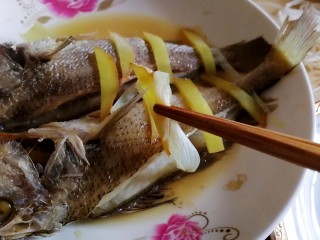 清蒸黄鱼,去掉蒸好的黄鱼背上的葱姜，倒掉盘子里了汤汁。