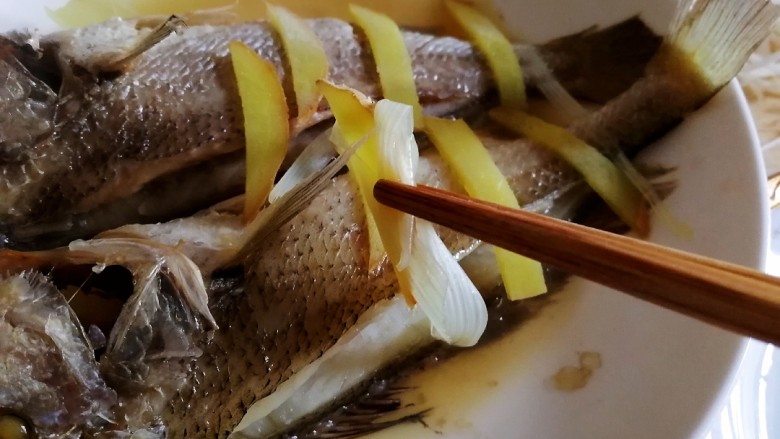 清蒸黄鱼,去掉蒸好的黄鱼背上的葱姜，倒掉盘子里了汤汁。
