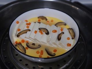 豆腐鸡蛋羹,蒸至蛋液凝固了摆上些香菇片和胡萝卜丁，继续蒸5分钟