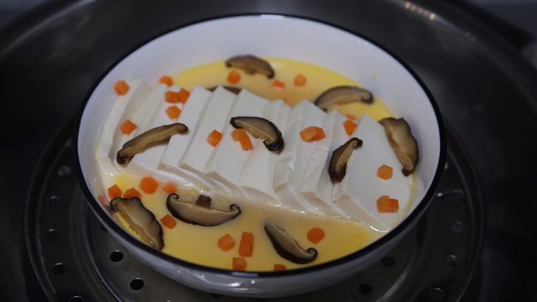 豆腐鸡蛋羹,蒸至蛋液凝固了摆上些香菇片和胡萝卜丁，继续蒸5分钟