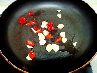 猪肉炒小白菜,锅中放入少量油炒香蒜瓣和红椒 
