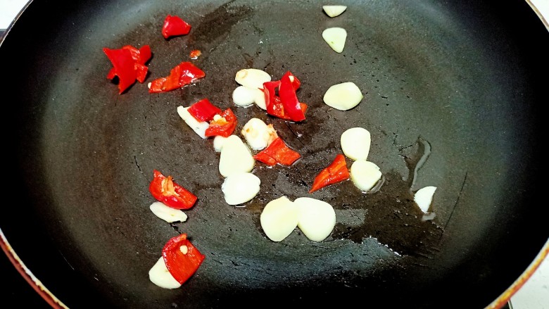 猪肉炒小白菜,锅中放入少量油炒香蒜瓣和红椒 