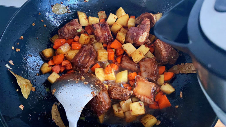 土豆排骨焖饭,加入土豆和胡萝卜块翻炒一会。加入没过材料的开水。