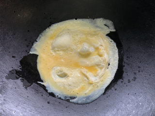 酸豆角炒鸡蛋,旋转油锅，让蛋液顺着边沿延展来了。两边煎熟后出锅。