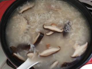 香菇鸡肉粥,快速用勺子搅拌均匀，盖上盖子继续煮。