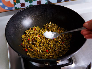 酸豆角炒肉末,酸豇豆入锅翻炒均匀，加入白糖提鲜增香，继续翻炒。