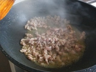 酸豆角炒肉末,倒入肉丁炒均匀变色。