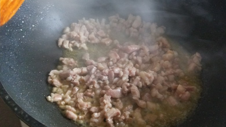 酸豆角炒肉末,倒入肉丁炒均匀变色。