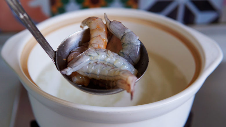 潮汕海鲜粥,大约煮二十分钟，大米完全开花了，这是把虾放入锅里。