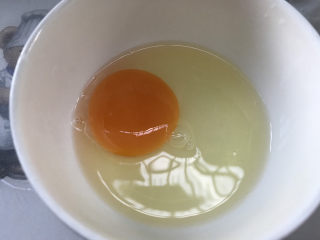 酸豆角炒鸡蛋,磕一个鸡蛋进碗中