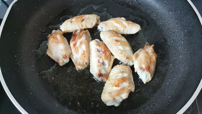 蒜香鸡翅,锅中倒入少许油，放入鸡翅两面煎至金黄